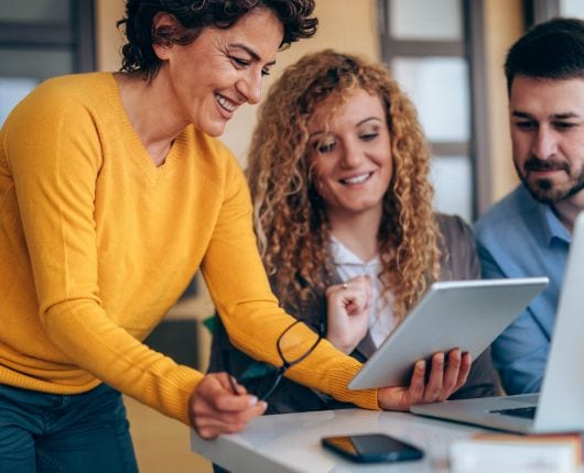 Three people looking at a computer and smiling.